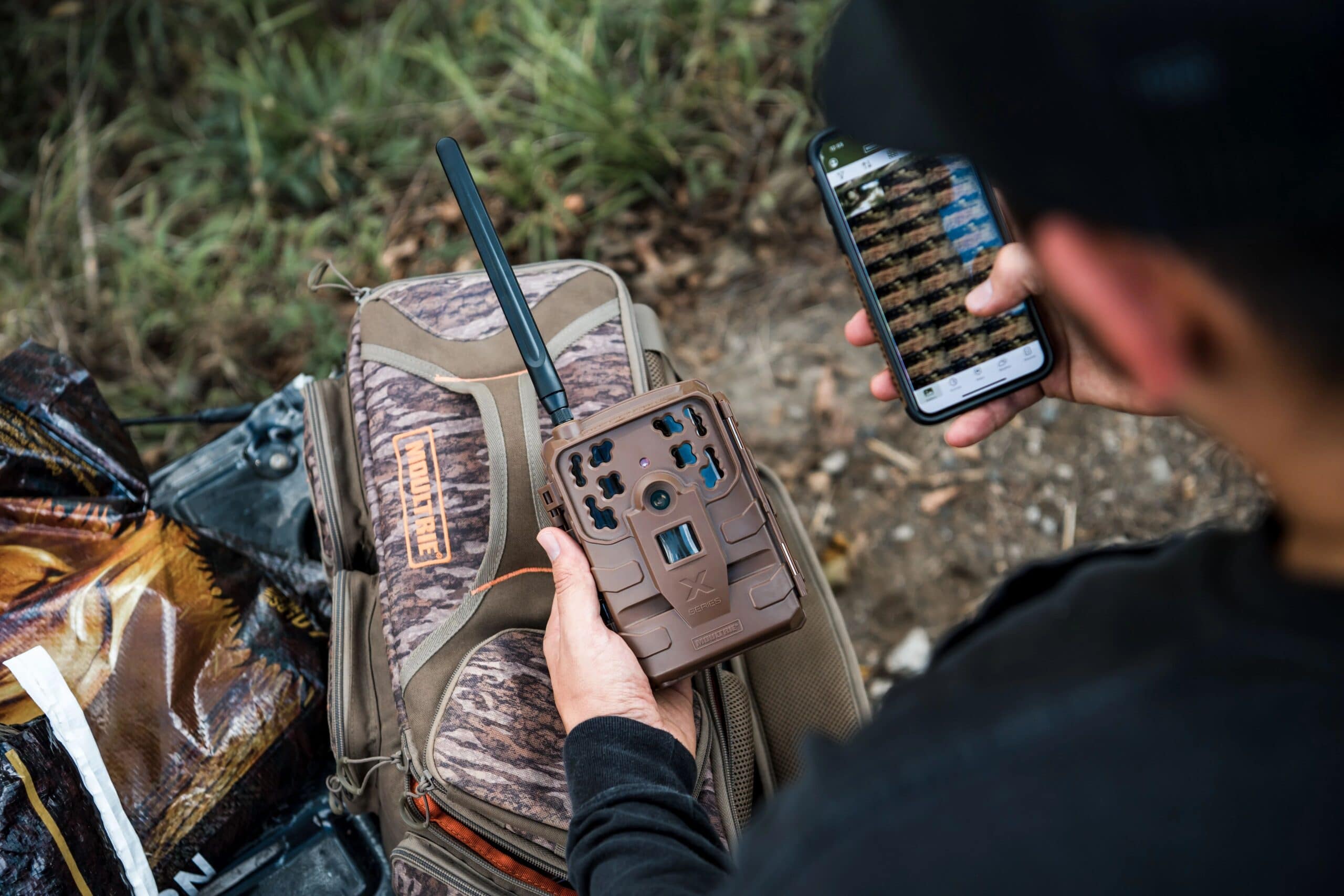 Man holding his Moultrie Mobile Cellular Trail Camera while scrolling through images on the app